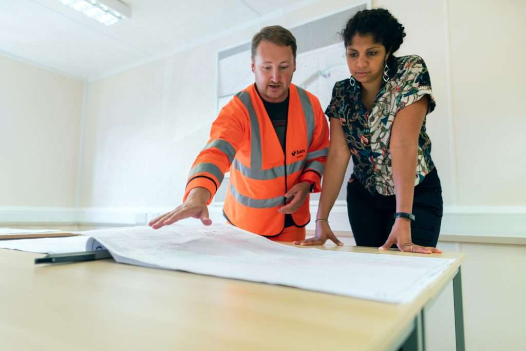 Two people looking at a construction plan for metal building