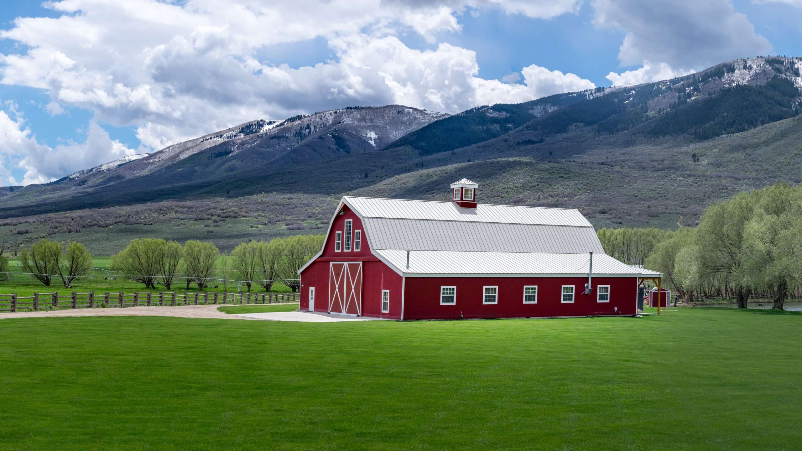 A beautiful red and white metal barn with a mountain background