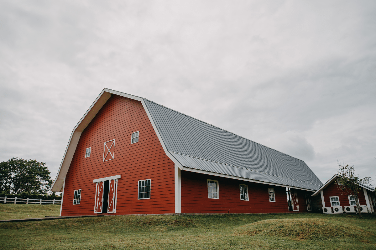 A large orange and gray metal barn in a vast field