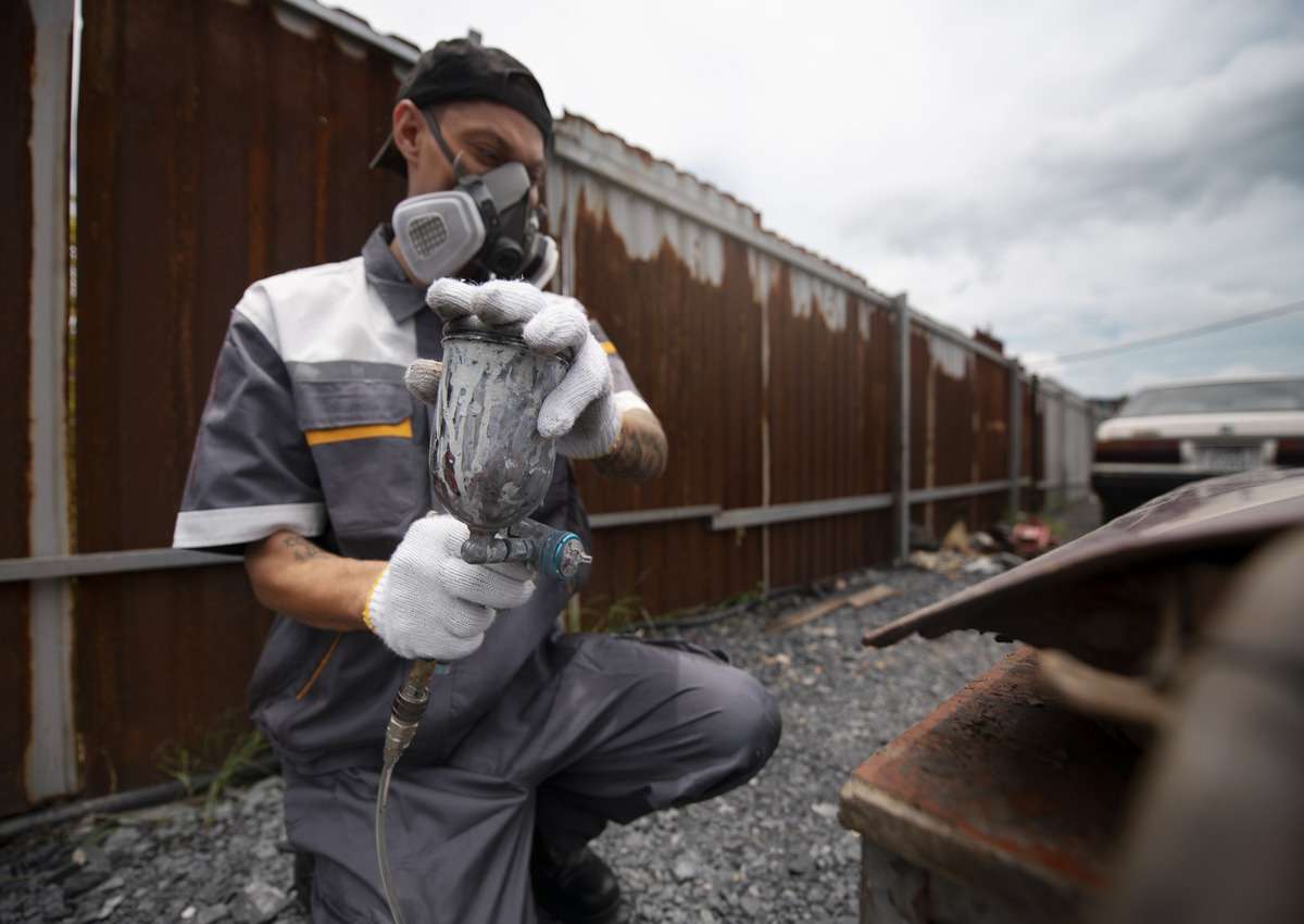 A man applying rust inhibitors before painting to prevent from corrosions