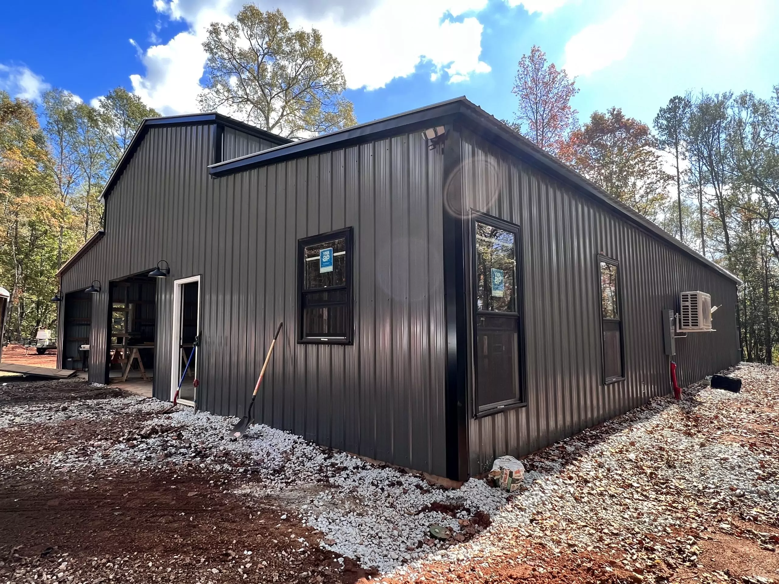 A gray-colored metal barn in the forest.