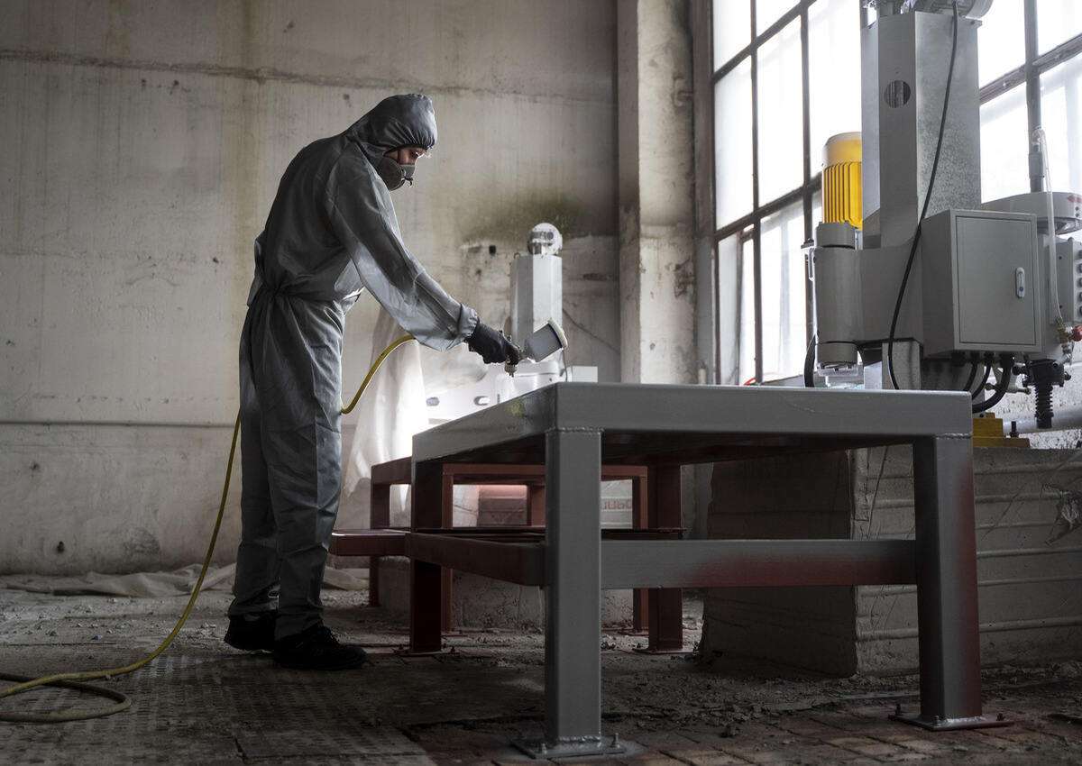 A worker applying anti-corrosion coatings to metal garage wall panels