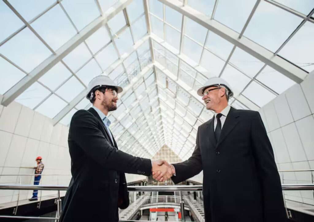 A businessman shaking hands with a contractor after completing the insulation job on the steel building