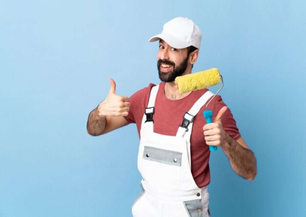 A worker with a paint roller giving a thumbs-up sign