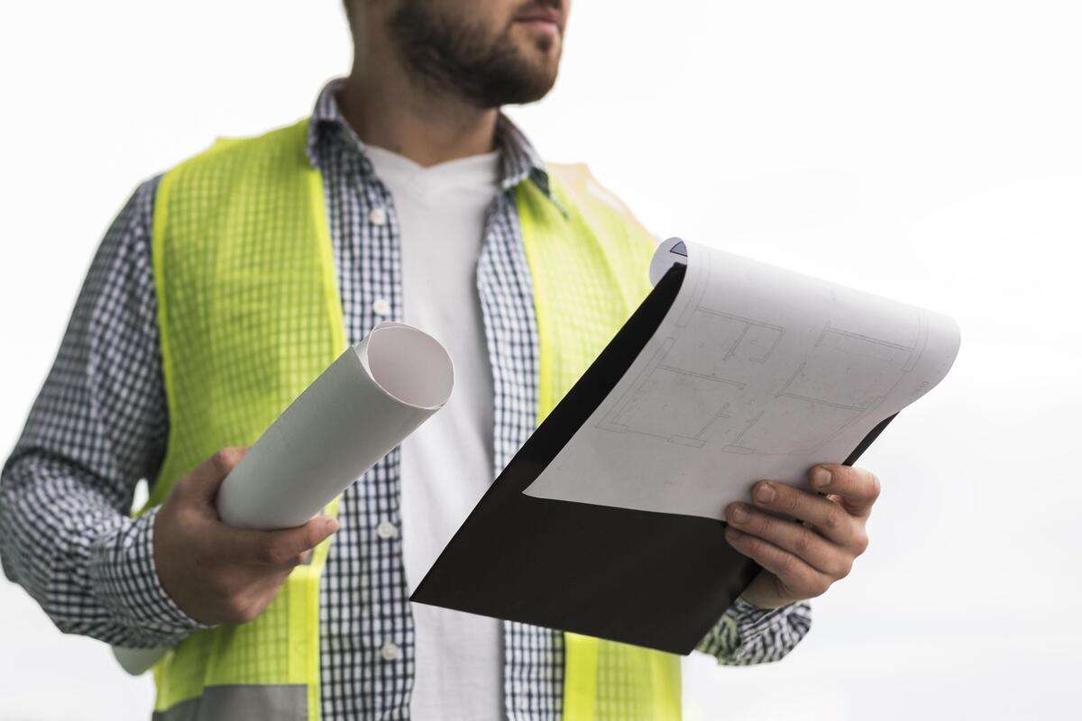 A person holding blueprints and permits for a steel building construction project.