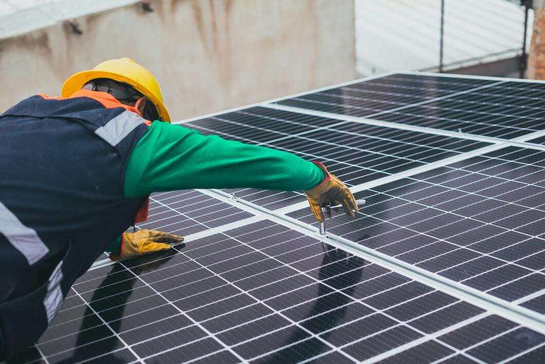 A person installing solar panel on a metal building