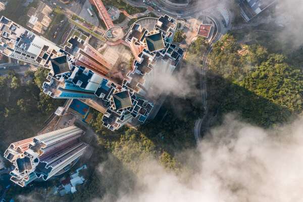 Aerial view of metal buildings beside forest and fog.