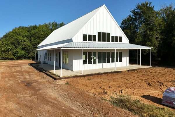 White barndominium under construction on cleared rural land.