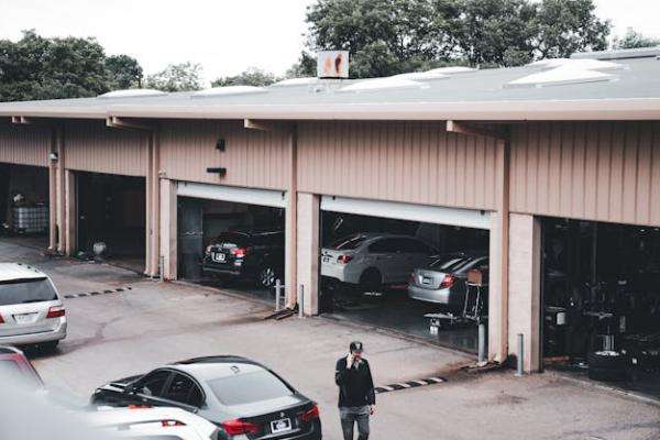 a car service center with multiple cars parked inside garages and a person walking outside