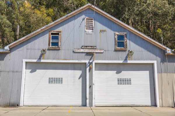 barndominium-style structure with industrial siding and symmetrical garage entrances