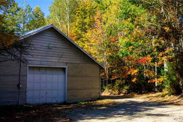 metal-sided barndominium surrounded by vibrant fall foliage on a forested property
