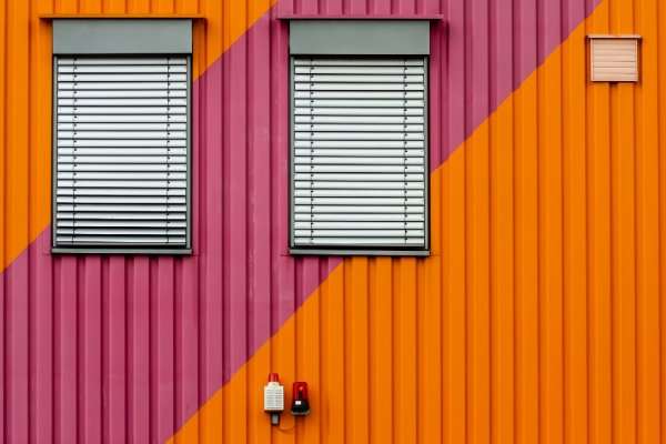 vibrant barndominium exterior with diagonal orange and pink metal siding and window blinds