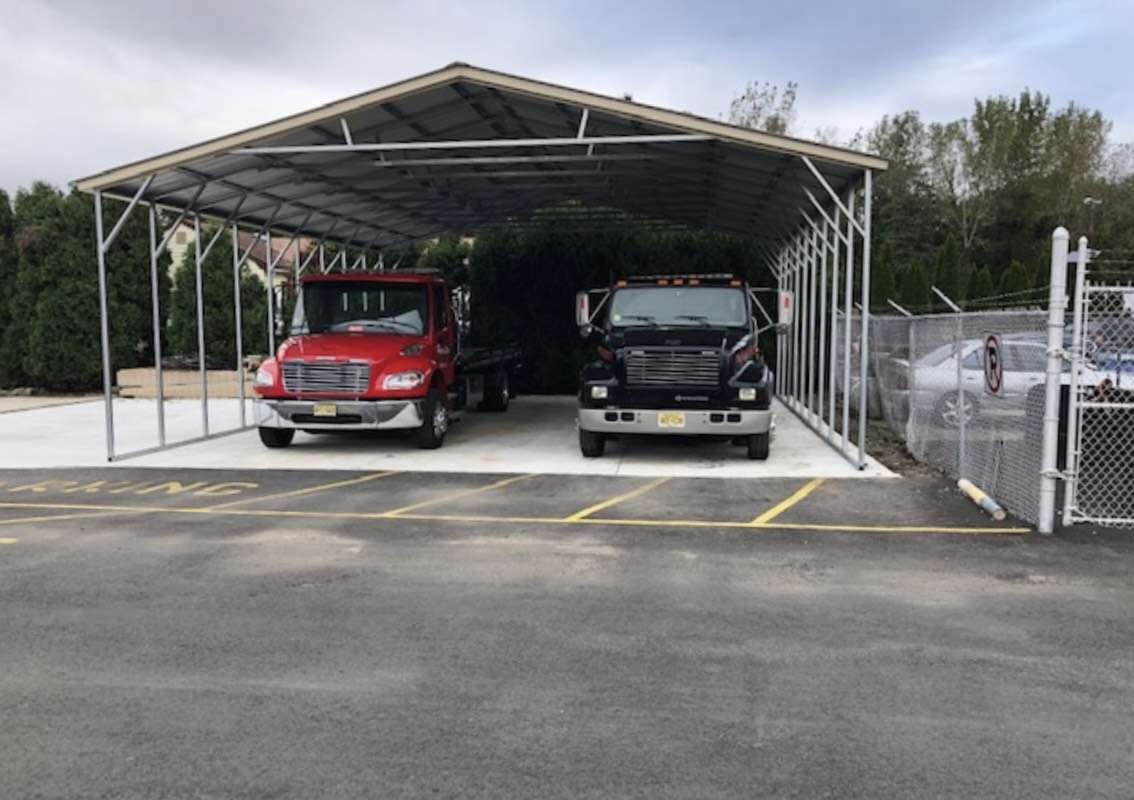 Two trucks parked in a metal carport