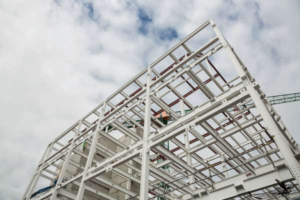 Steel frame of a large metal building under construction with open sky background.